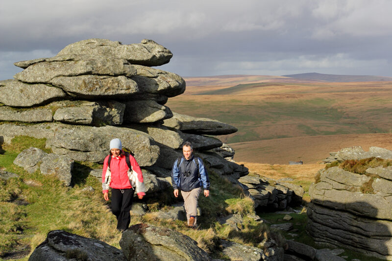 Hügellandschaft mit zwei Wanderern in Dartmoor (Grafschaft West Devon)