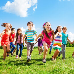 Kinder laufen über Wiese im Sommer