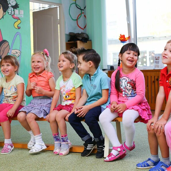 lachende Kinder auf einer Bank im Kindergarten