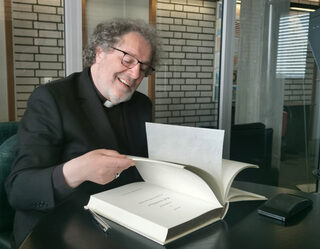 Weihbischof Rolf Steinhäuser blättert interessiert durch das Gästebuch der Stadt Wesseling, bevor er sich selbst einträgt.